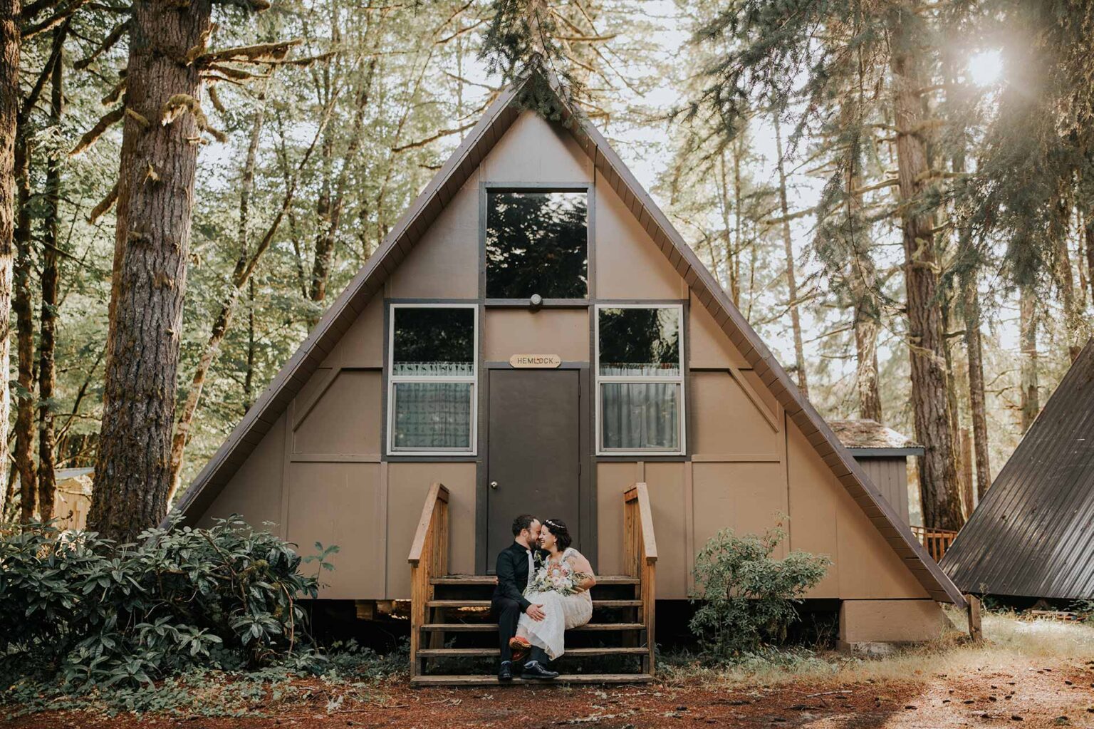 A newly-married couple sitting on the steps of an a-frame cabin at Camp Lutherwood Oregon