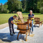 Two women staining chairs at work day