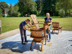 Two women staining chairs at work day