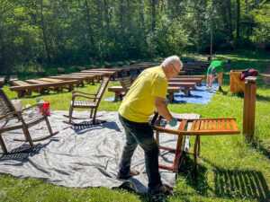 Two men staining chairs at work day