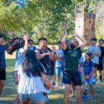 Group of campers cheering with their hands raised