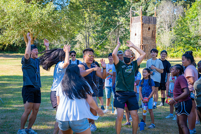 Group of campers cheering with their hands raised